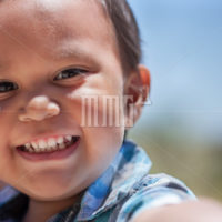 Handsome young boy with great smile and full set of baby teeth looking excited outdoors during summer