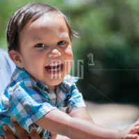 Young son toddler reaching, touching, playing and enjoying summer with mother outdoor in a park, looking enthusiastic and laughing