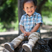 Cute mexican boy with plaid shirt and great healthy smile with baby teeth sitting outdoors during summer in california national park