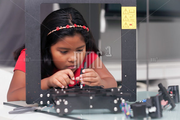 Young girl, 8 year old assembling a 3D printer kit for STEM summer camp