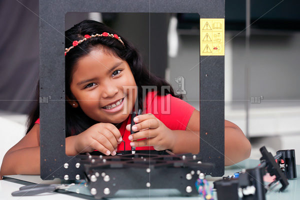 Happy 8 year old girl building a 3D printer kit for summer engineering camp or class